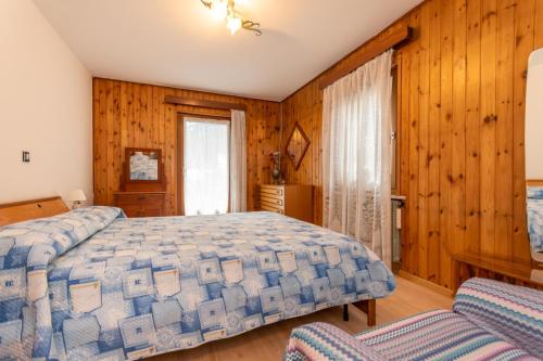 a bedroom with a bed and wooden walls at Appartamento Alba sulle Dolomiti in Falcade