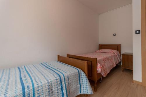two beds in a room with white walls and wooden floors at Appartamento Alba sulle Dolomiti in Falcade