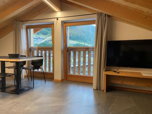 a living room with a television and a table and a balcony at Casa Montana in Commezzadura