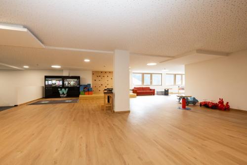 an empty living room with wooden floors and a tv at Hotel Kristall in Grossarl