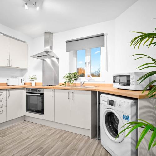 a kitchen with white cabinets and a washer and dryer at Stylish Two Bedroom Apartment - Sleeps Three - Secure Parking - Fast WiFi 53C in Sleightholme