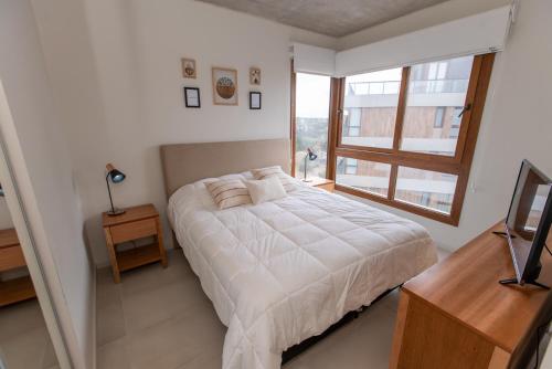 a bedroom with a white bed and a window at Frente al mar in Pinamar