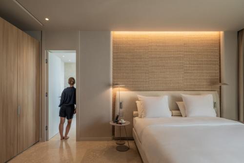 a woman standing in a bedroom with a large bed at Green Coast Hotel MGallery Collection in Vlorë