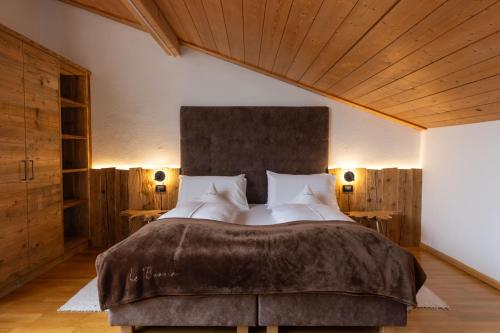 a bedroom with a large bed and wooden ceilings at La Bercia Alpine Lodge & Spa in La Villa