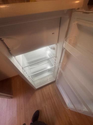 an empty refrigerator with its door open on a wooden floor at Maisonnette in Limours