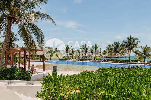 un complexe avec piscine et palmiers dans l'établissement CORAL Beachfront 2BDR with pool by Casa Paraiso, à Cancún