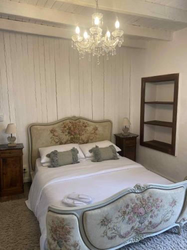 a bedroom with a large bed with a chandelier at Le Puy Chevalier - La Belle Vue in Oradour-sur-Vayres