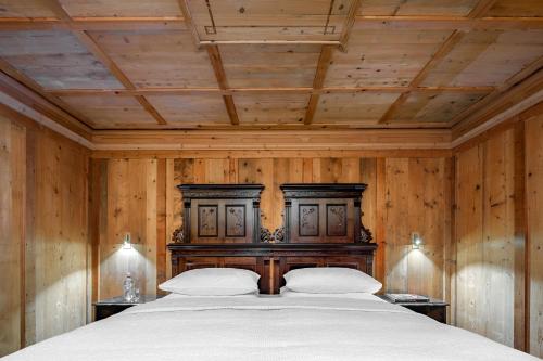 a bedroom with a large bed with wooden walls at Hotel La Perla: The Leading Hotels of the World in Corvara in Badia