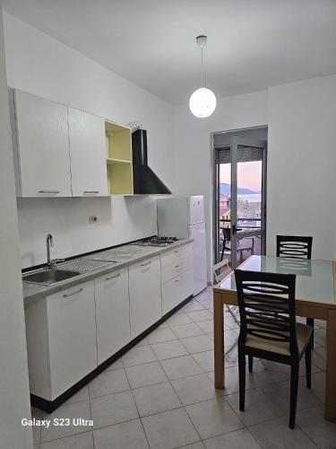 a kitchen with white cabinets and a table and a dining room at Tomi's Orikum Apartments in Orikum