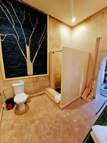 a bathroom with a toilet and a painting of a tree at Riad Kasbah privilège and SPA in Marrakech