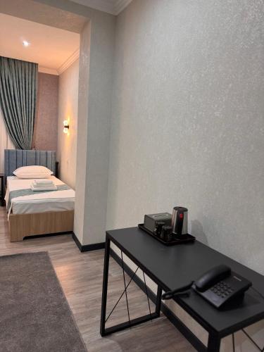 a room with a desk and a bed with a phone at Mehran in Andizhan
