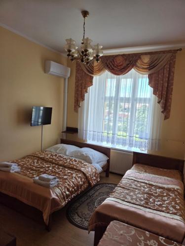 a bedroom with two beds and a large window at Pałac Makowice in Świdnica