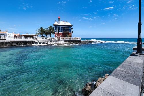a lighthouse in the water next to the ocean at Apartamento El Charcon A - 10 meters to the Beach By Lanzarote Vacation Homes in Arrieta