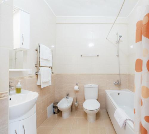 a white bathroom with a toilet and a tub and a sink at Asiya in Odesa