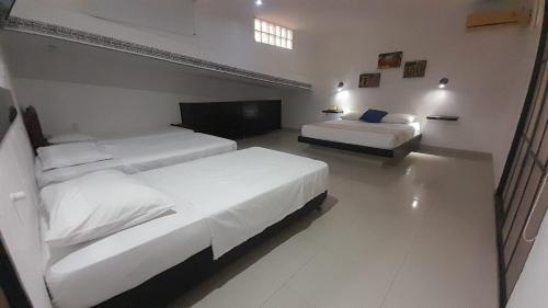 two beds in a hotel room with white walls at Sunset Taganga Hotel in Taganga