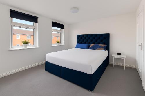 a bedroom with a large bed and two windows at Bright and Spacious King & Double Rooms, Free Private Parking, Close to Heathrow in Cranford