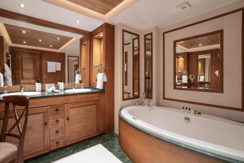 a bathroom with a tub and two sinks and a large mirror at Hotel Annapurna in Courchevel