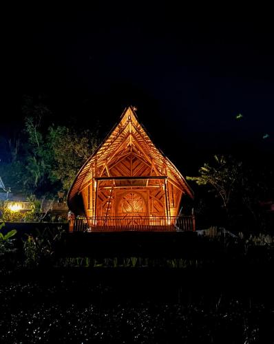 a wooden building with a lit up roof at night at Velonia Iseh in Sidemen