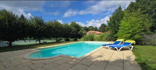 una piscina con due sedie a sdraio accanto di La Treille - Grand jardin avec Piscine & Tennis a Saint-Hilaire-du-Bois