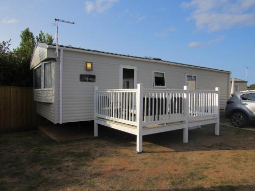 a small white house with a porch and a car at Caravan at Family Park WiFi, Parking in Dawlish Warren