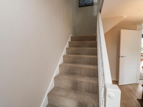 a staircase in a home with white walls and carpeted floors at Thurlestone, 1 Island View in Kingsbridge