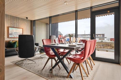 a dining room with a table and red chairs at Rorbuleilighet Lysøya 1H in Henningsvær