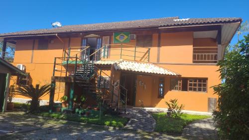 a yellow building with a staircase in front of it at Casarão Villa al Mare in Ubatuba