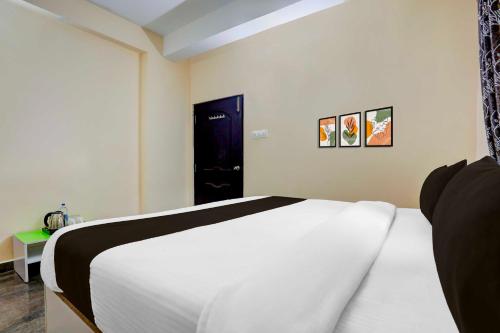 a bedroom with a white bed and a blue door at Hotel O Tirupati Railway Junction Y Stay Home Stay in Tirupati