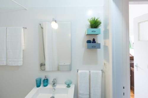 Un baño blanco con lavabo y espejo. en KOPKE 113, local & spacious 2Bed, en Oporto