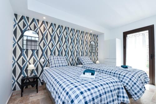 a bedroom with two beds with blue and white sheets at Résidence Le Jardin d'Eugénie in Sanary-sur-Mer