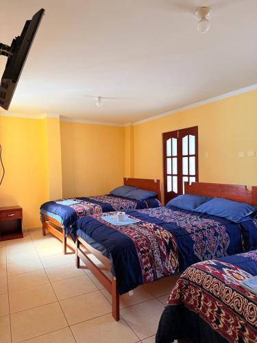 three beds in a room with yellow walls at Hostal La Alborada in Cajamarca