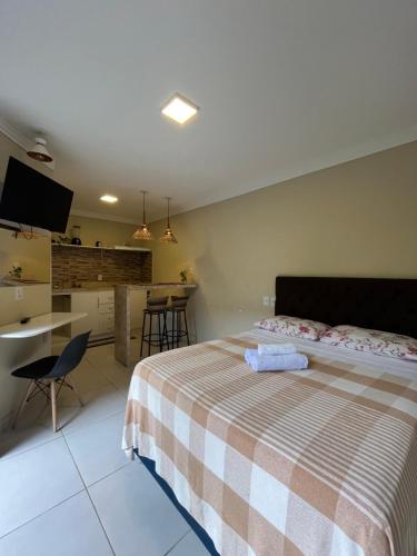a bedroom with a bed and a desk and a kitchen at Casinhas da Vila in Itacaré