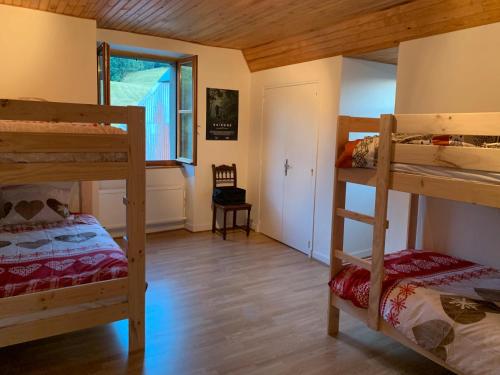 ein Zimmer mit drei Etagenbetten und einem Fenster in der Unterkunft Gîte À La Ferme Au Puy Mary in Mandailles