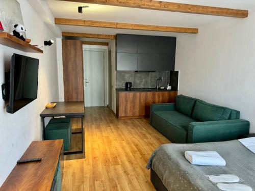 a living room with a green couch and a kitchen at Go-Gudauri The Atrium Residence in Gudauri
