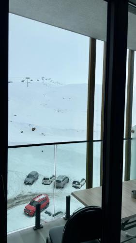 a view of cars parked in the snow from a window at Go-Gudauri The Atrium Residence in Gudauri