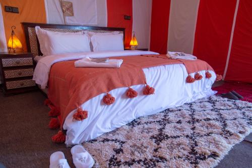 a bedroom with a large bed with shoes on it at Erg Chebbi Dunes Desert Camp in Merzouga