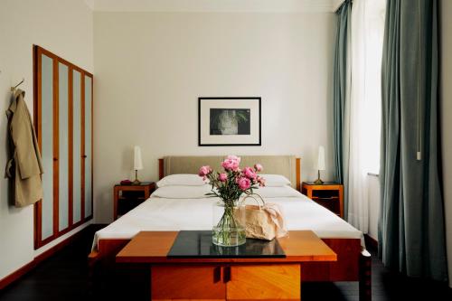 a bedroom with a bed with a vase of flowers on a table at Parkhotel Laurin in Bolzano