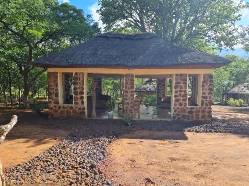 a small hut with a grass roof on a field at Mukuni Villas in Livingstone