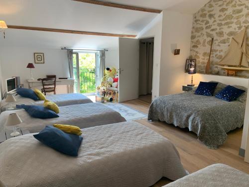 a bedroom with three beds with blue and yellow pillows at Chambre chez l'habitant dans MAS provençal avec piscine partagée en saison in Roquemaure
