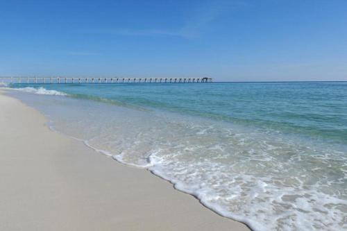 a sandy beach with a pier in the ocean at Sand Dollar E201 in Pensacola Beach