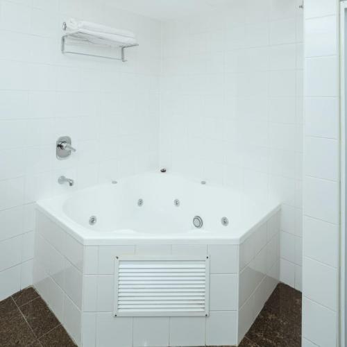 a white bathroom with a tub and a sink at One bedroom Hospitality Suite in Sydney