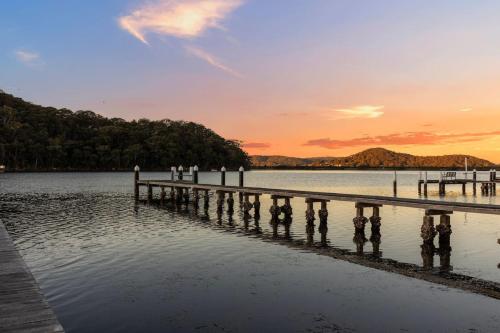 a dock on a lake with a sunset in the background at New Waterfront Escape with Private Jetty in Woy Woy