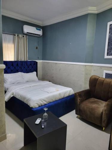 a bedroom with a bed and a chair and a table at International Royal Hotel in Owerri