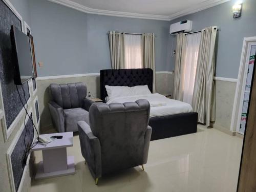 a bedroom with a bed and a couch and a chair at International Royal Hotel in Owerri