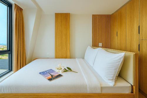 a bedroom with a bed with a book and flowers on it at Amory Dalat Hotel in Khu Chi Lăng