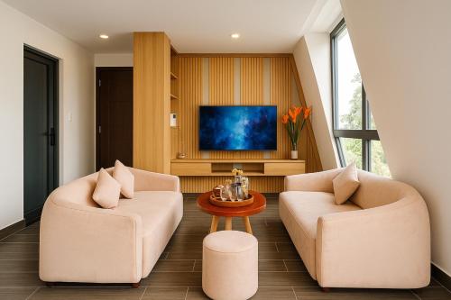 a living room with two chairs and a tv at Amory Dalat Hotel in Khu Chi Lăng