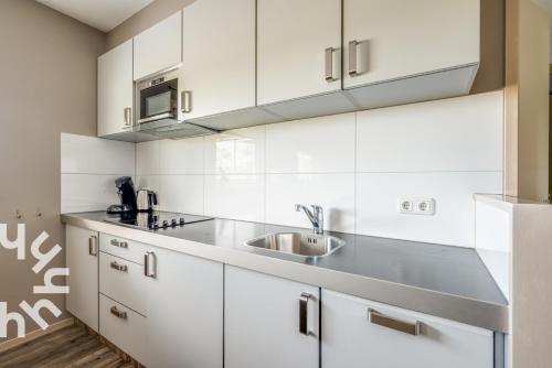 a kitchen with white cabinets and a sink at de Paardekracht in Serooskerke