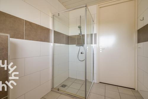 a shower with a glass door in a bathroom at de Paardekracht in Serooskerke