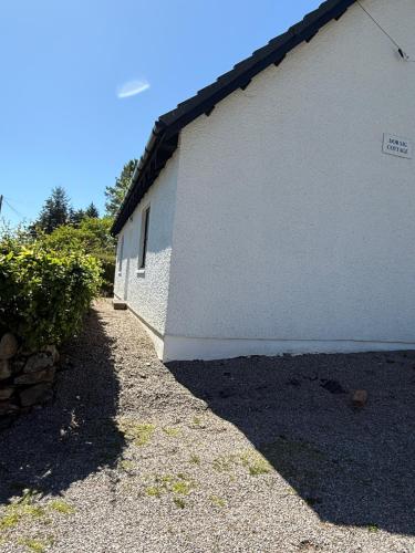 a white building with a sidewalk next to it at Highland Nook in Fort William