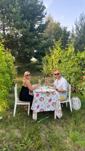 a man and woman sitting at a table with wine glasses at Apartamenty i Winnica - Siedlisko Na Polanie in Lipka Wielka